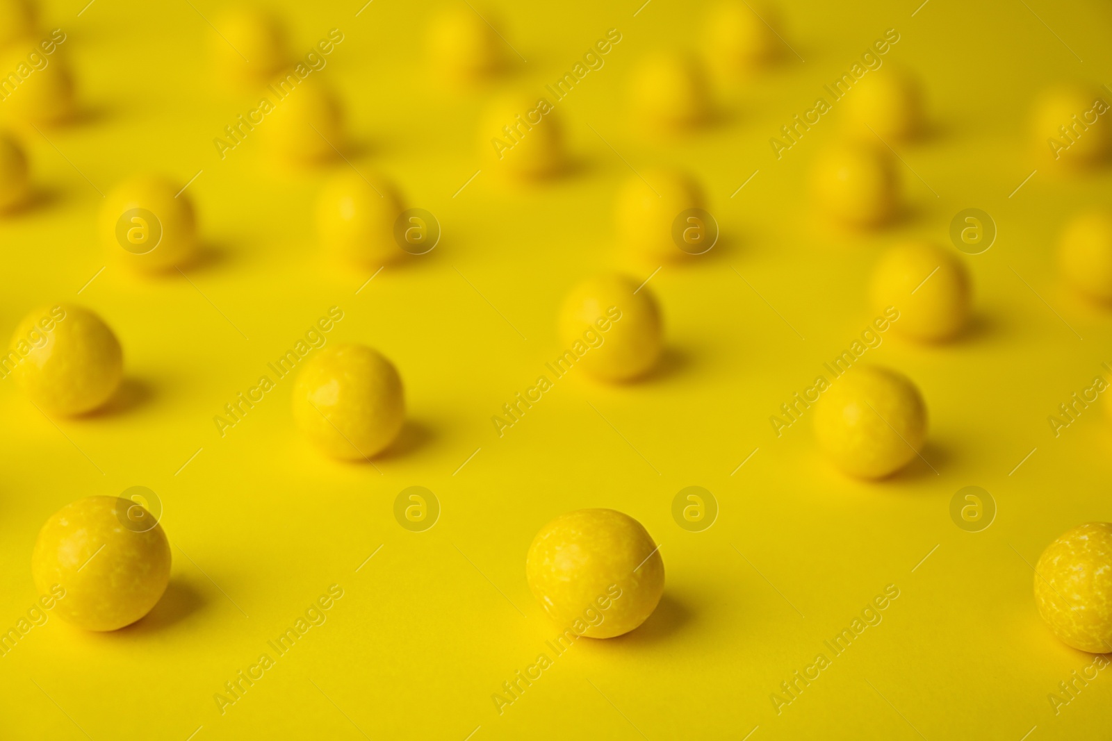 Photo of Delicious lemon chewing gums on yellow background, closeup