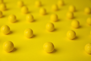 Photo of Delicious lemon chewing gums on yellow background, closeup