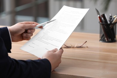 Photo of Man reading document at table in office, closeup. Signing contract