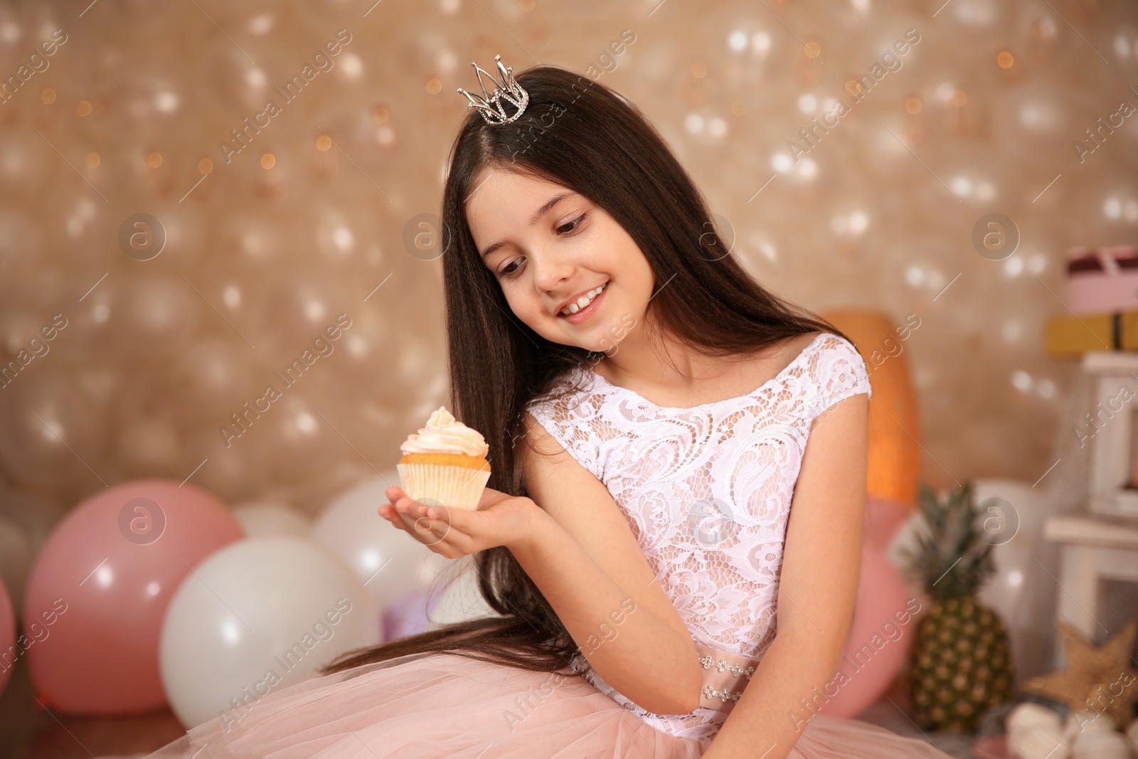 Photo of Happy little girl with birthday cupcake in beautifully decorated room at home