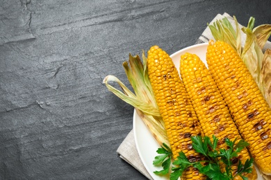 Tasty grilled corn on black table, space for text