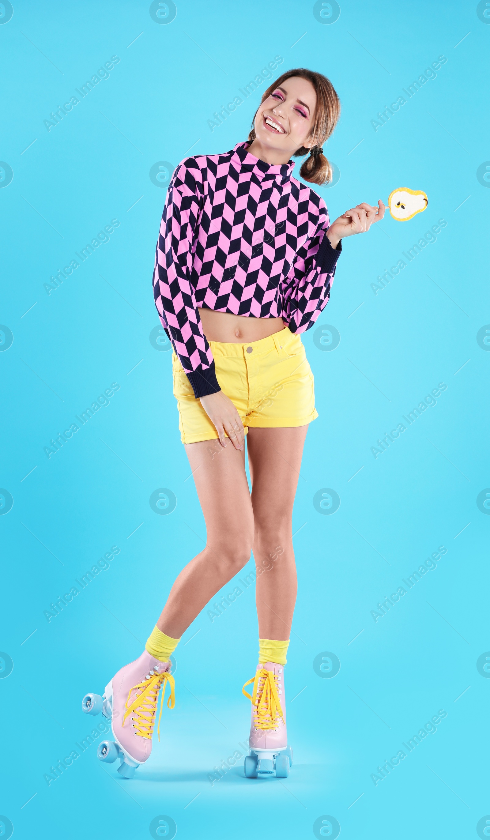 Photo of Young woman with lollipop and retro roller skates on color background