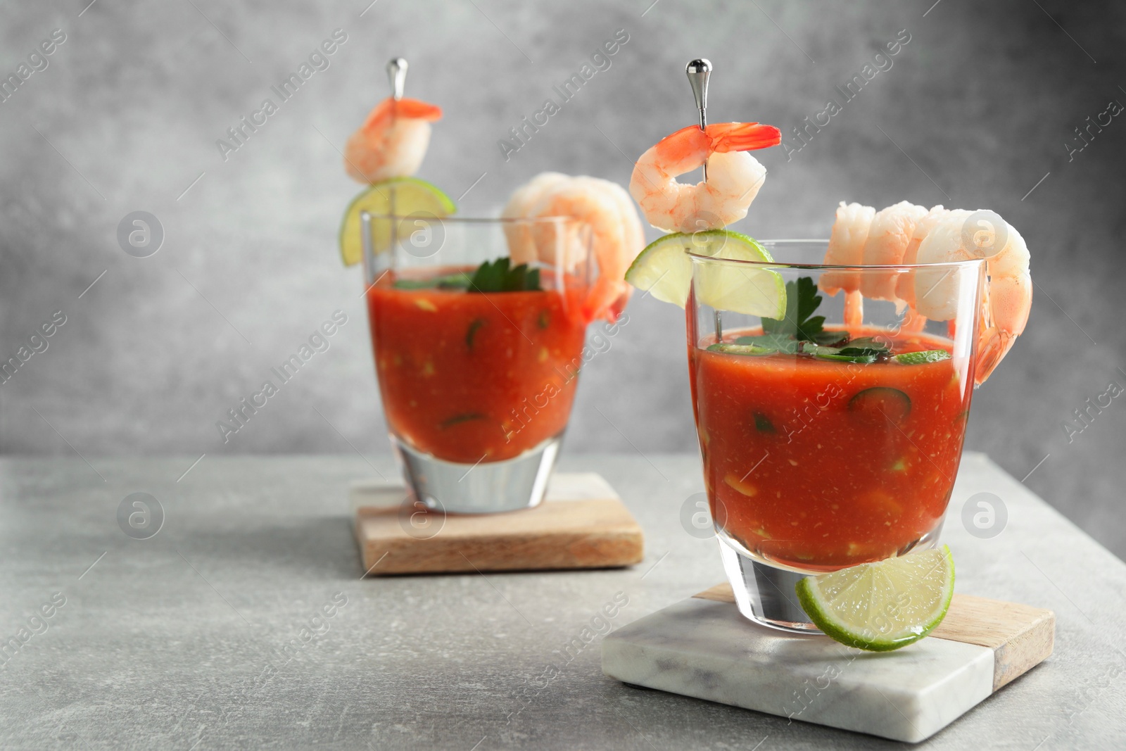 Photo of Tasty shrimp cocktail with sauce in glasses and lime on light grey table, space for text