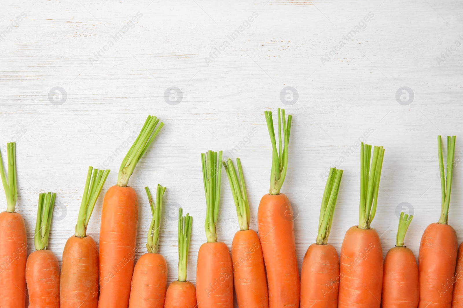 Photo of Ripe carrots on wooden background, top view