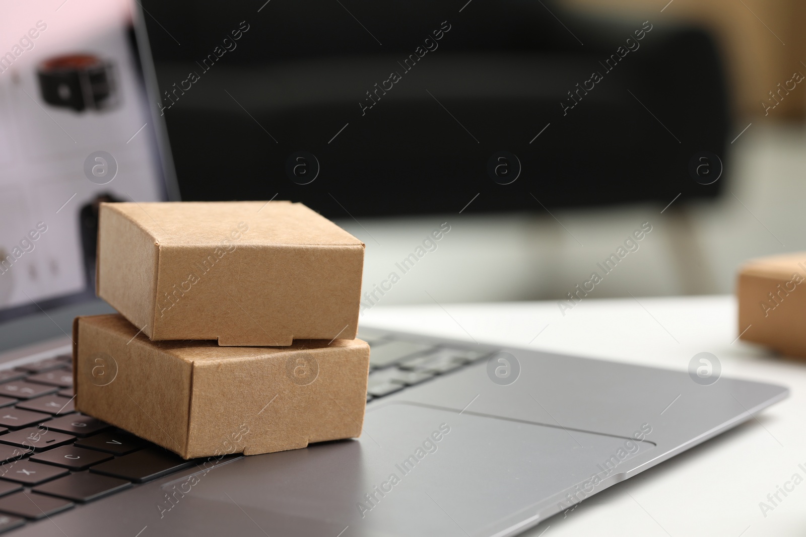 Photo of Online store. Small parcels and laptop on white table, closeup. Space for text