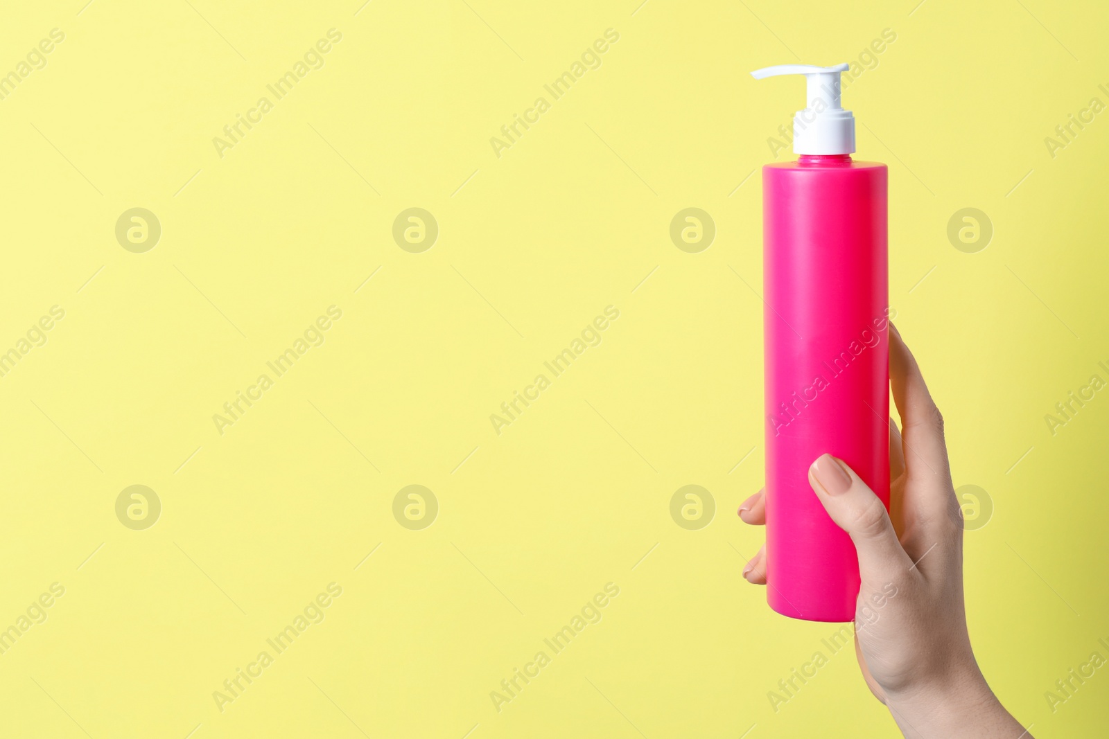 Photo of Woman holding spray bottle with hair thermal protection against pale yellow background, closeup. Space for text