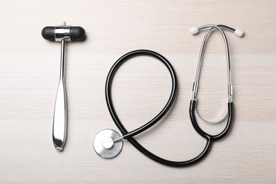 Photo of Reflex hammer with stethoscope on wooden background, flat lay. Nervous system diagnostic