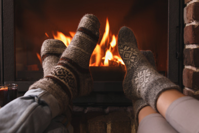 Photo of Couple resting near fireplace indoors, closeup. Winter vacation