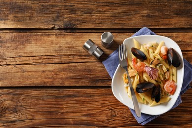 Delicious pasta with seafood served on wooden table, flat lay. Space for text