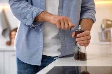 Man using manual coffee grinder in kitchen, closeup