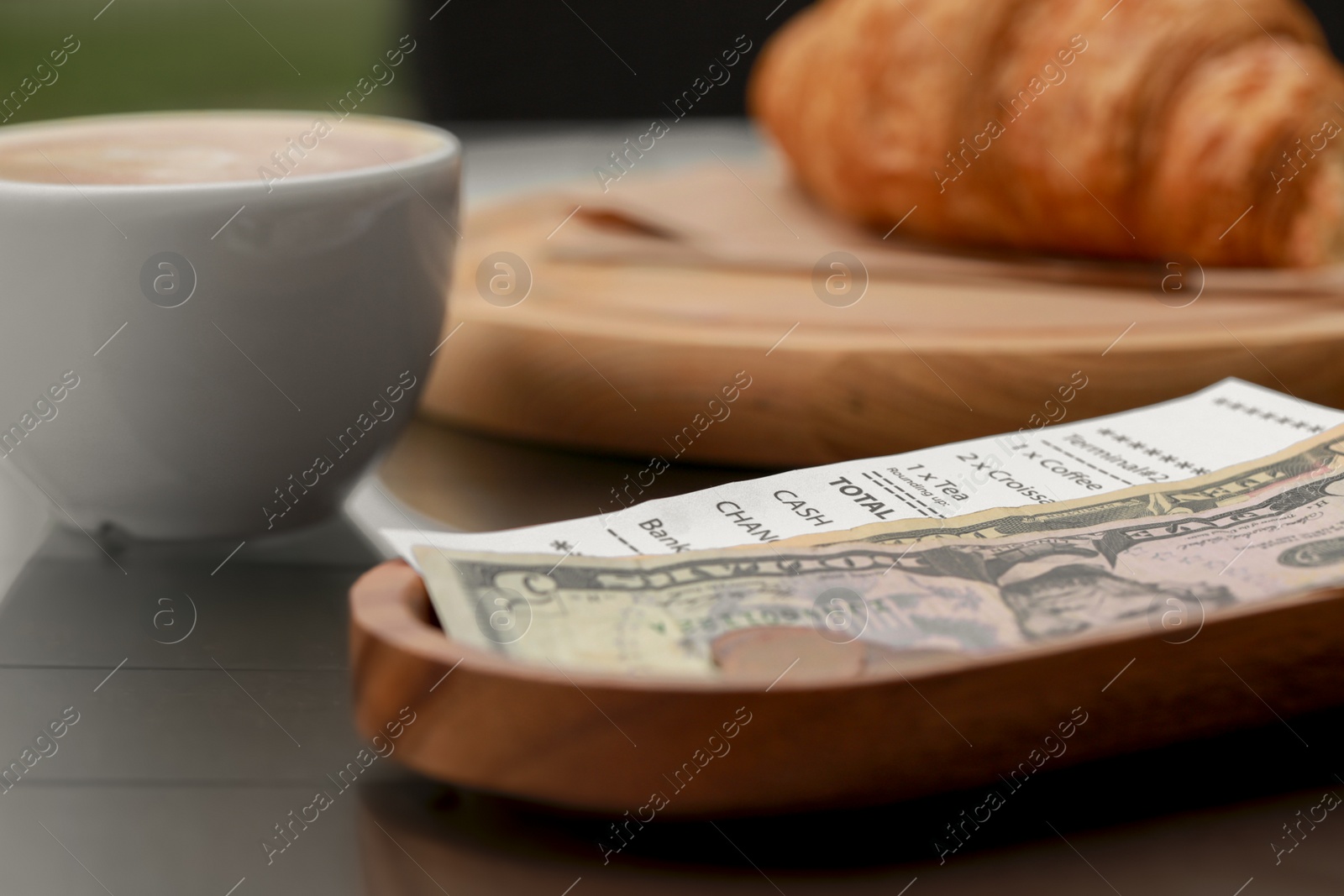 Photo of Tips and receipt on wooden table, closeup