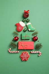 Photo of Christmas tree silhouette of fir branches and festive decoration on green background, flat lay