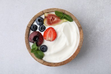 Bowl with yogurt, berries, fruits and mint on light grey table, top view