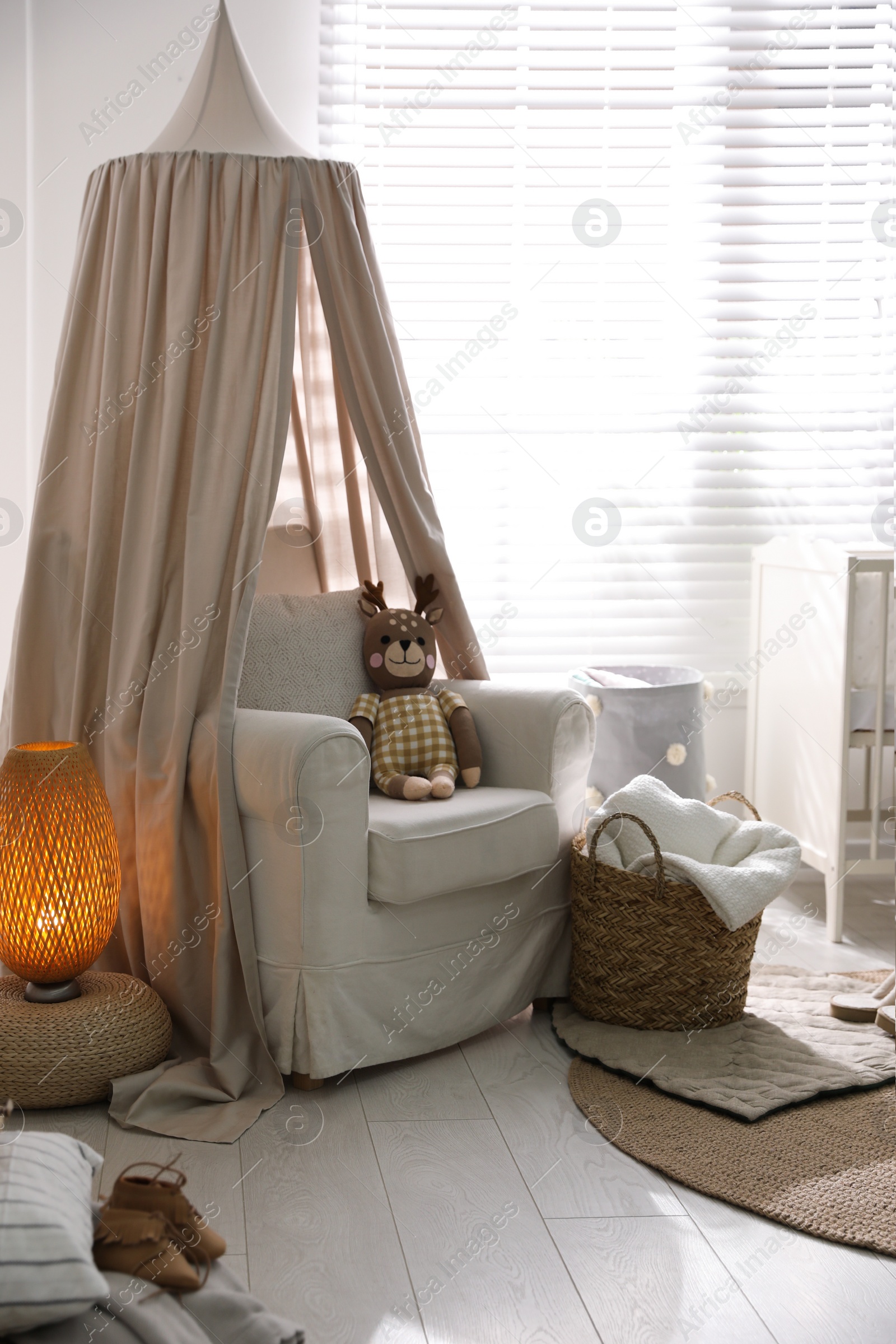 Photo of Stylish baby room interior with toys and comfortable armchair