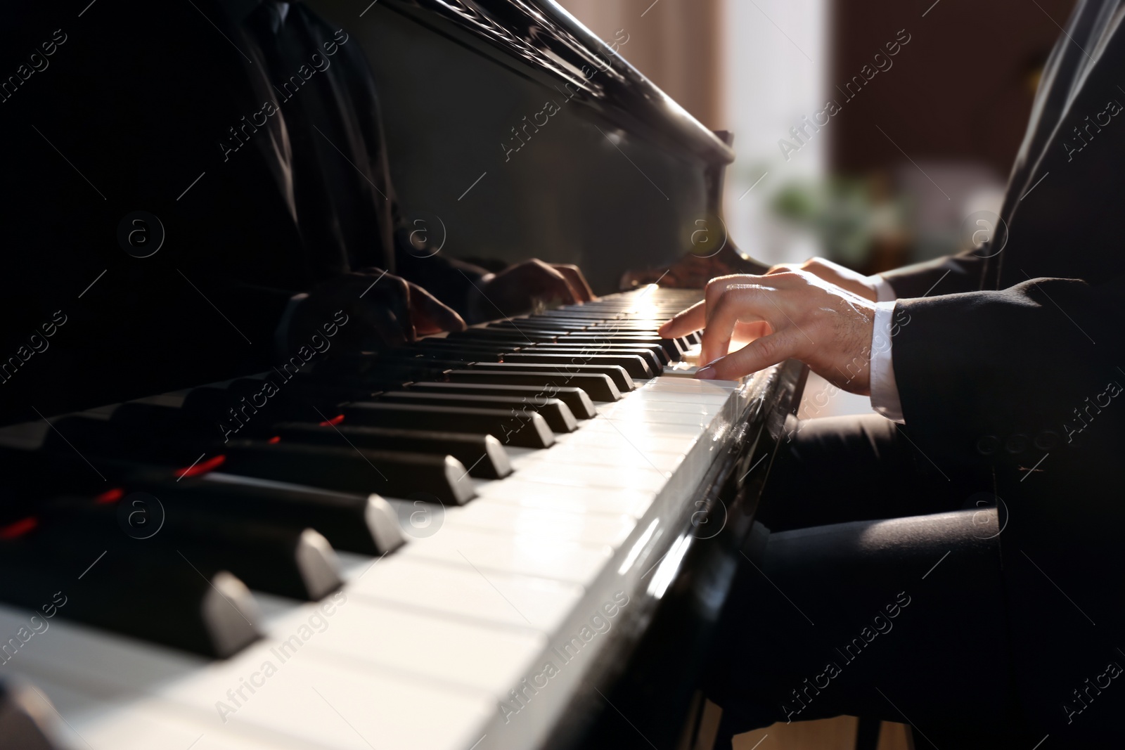 Photo of Man playing piano indoors, closeup. Talented musician