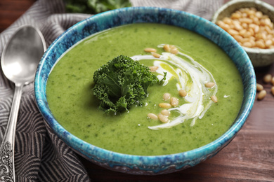 Photo of Tasty kale soup served on wooden table, closeup