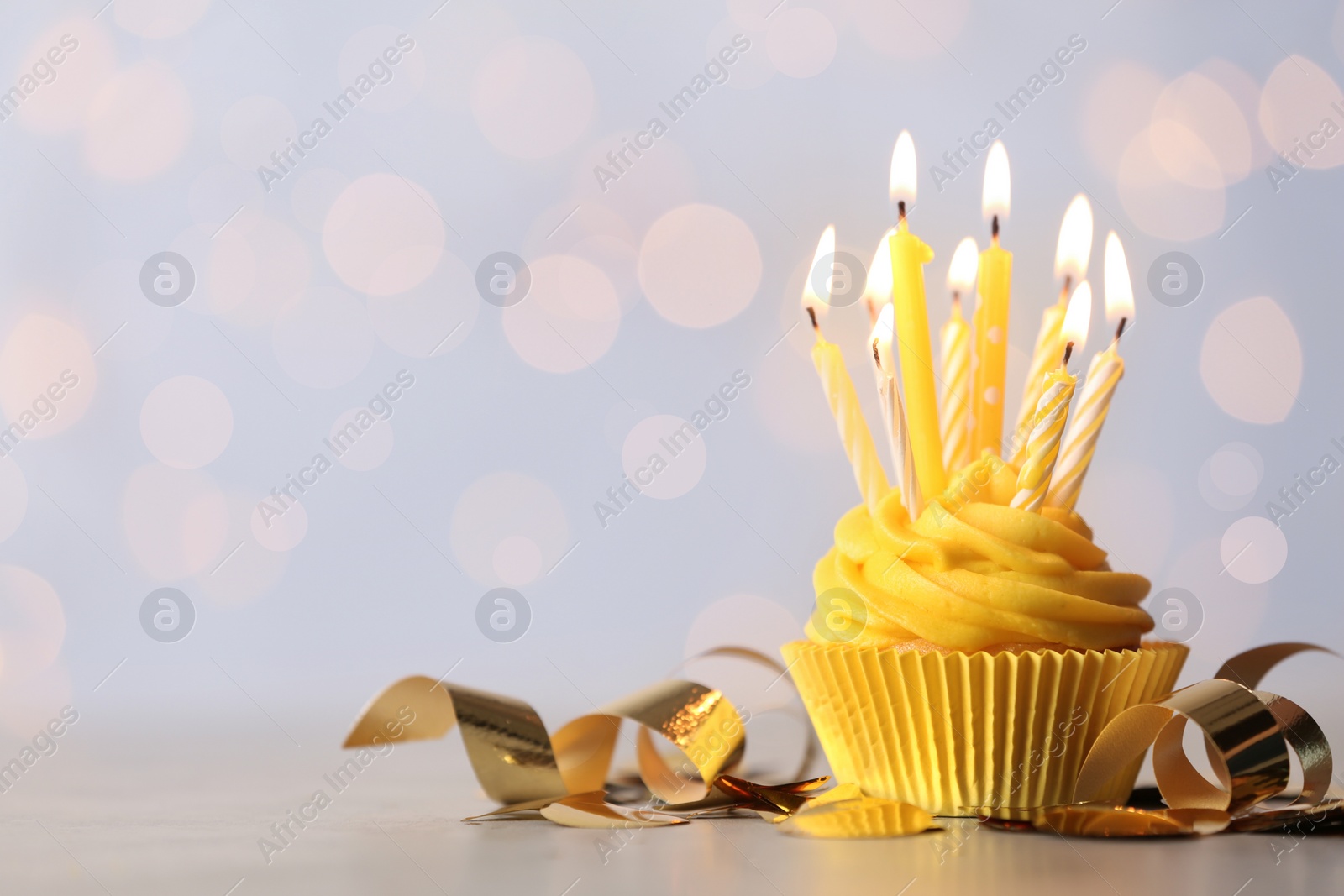 Photo of Delicious birthday cupcake with burning candles on table. Space for text