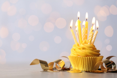Photo of Delicious birthday cupcake with burning candles on table. Space for text