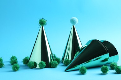 Party hats with green pompoms on light blue background