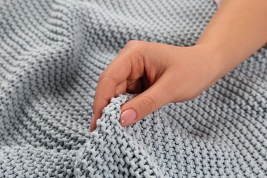 Photo of Woman touching soft grey knitted fabric, closeup