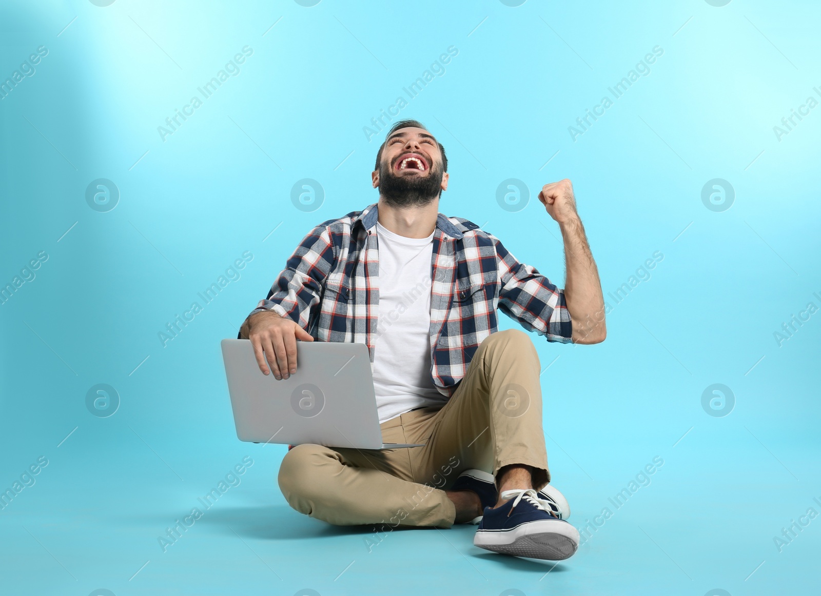 Photo of Emotional young man with laptop celebrating victory on color background