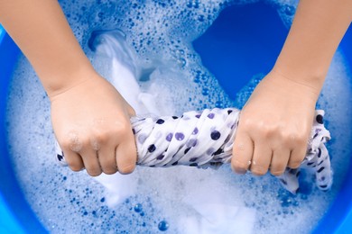 Woman wringing garment over basin, closeup. Hand washing laundry