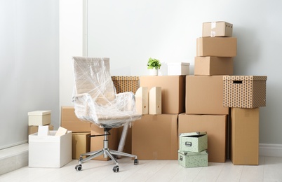 Photo of Cardboard boxes and packed chair indoors. Moving day