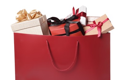 Dark red paper shopping bag full of gift boxes on white background, closeup