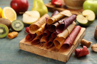 Photo of Composition with delicious fruit leather rolls on blue wooden table
