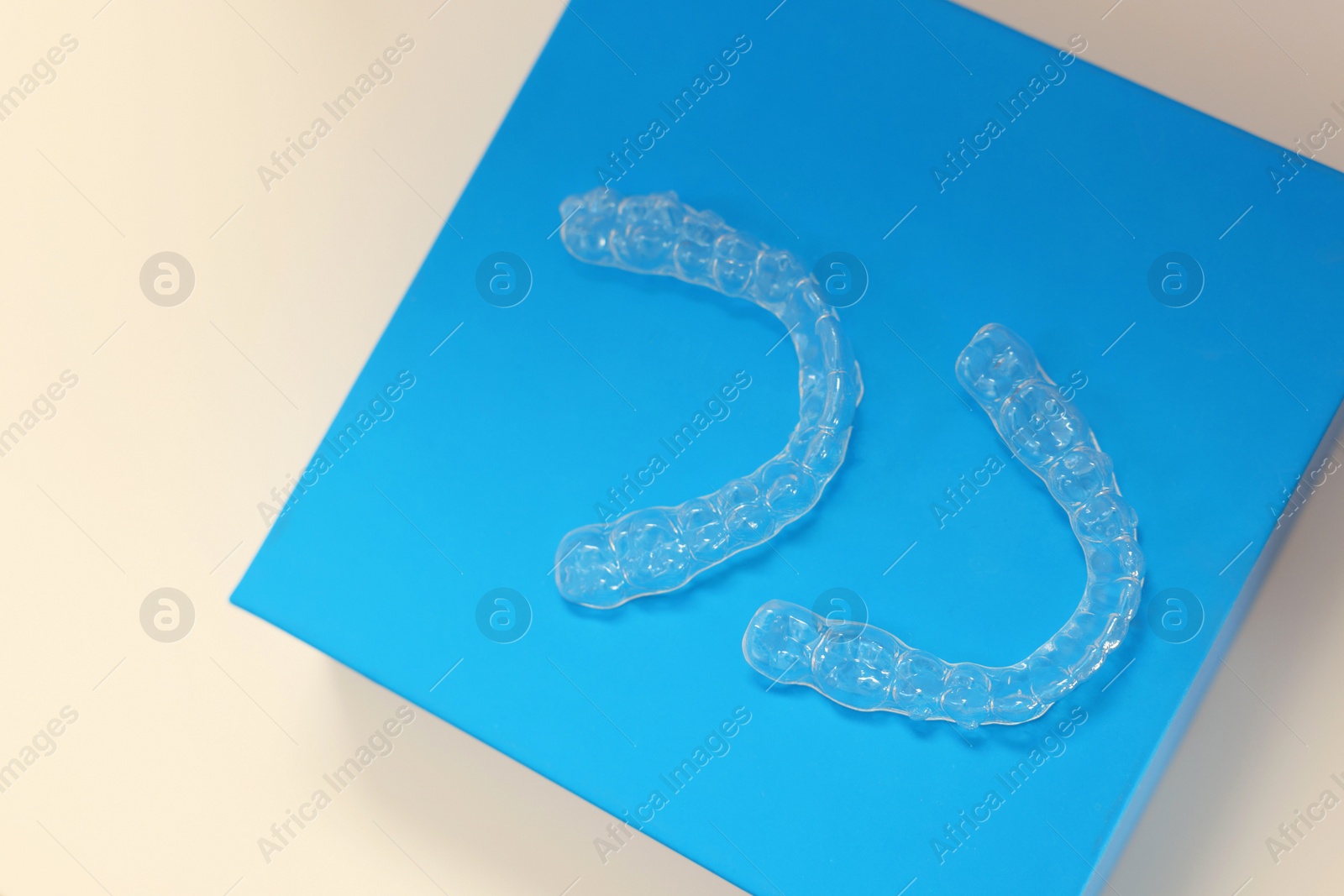 Photo of Transparent dental aligners on beige background, top view. Space for text