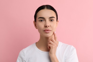 Photo of Woman with dry skin checking her face on pink background