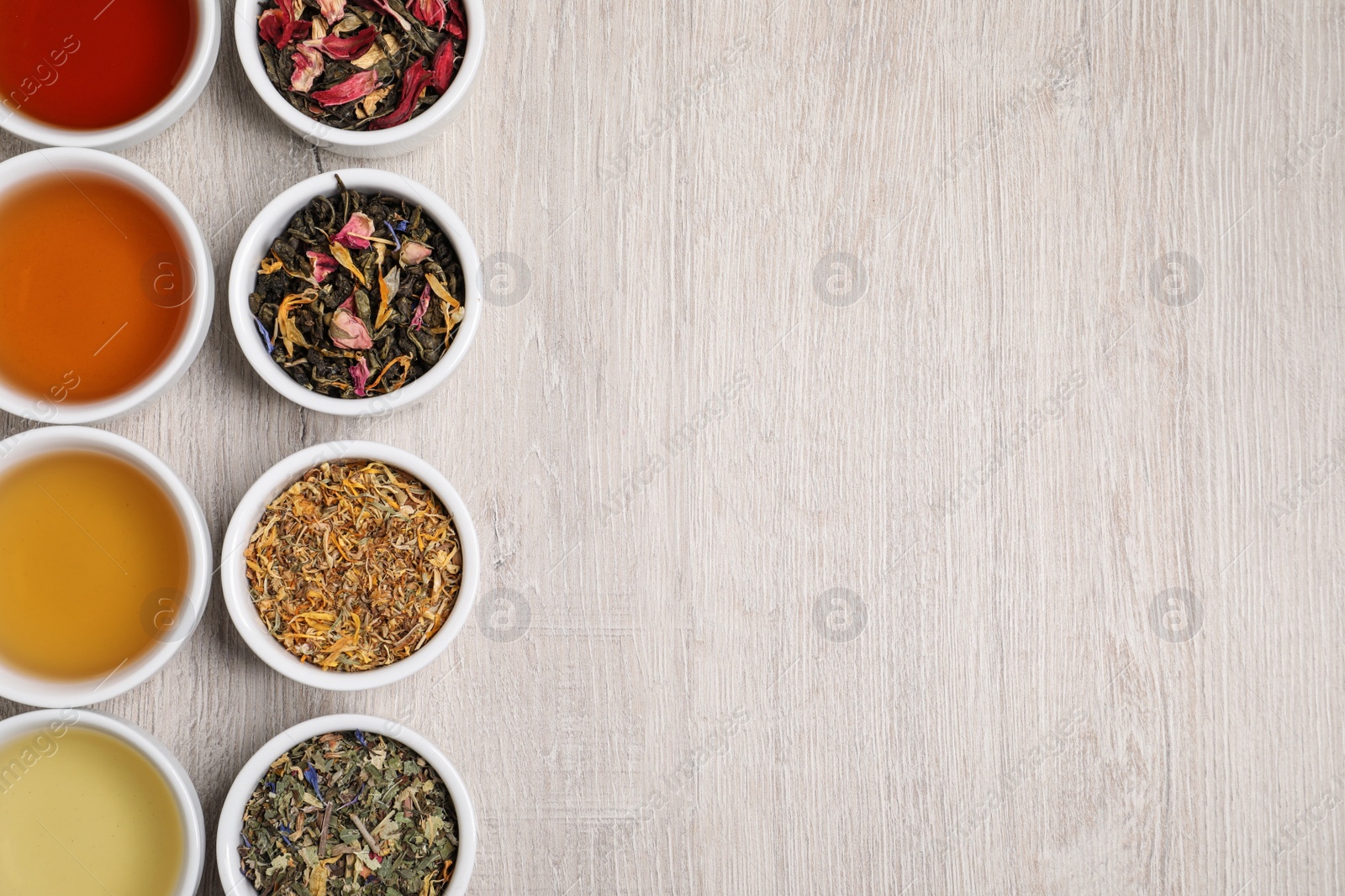 Photo of Flat lay composition with different freshly brewed teas and dry leaves on wooden table. Space for text