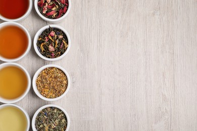 Photo of Flat lay composition with different freshly brewed teas and dry leaves on wooden table. Space for text