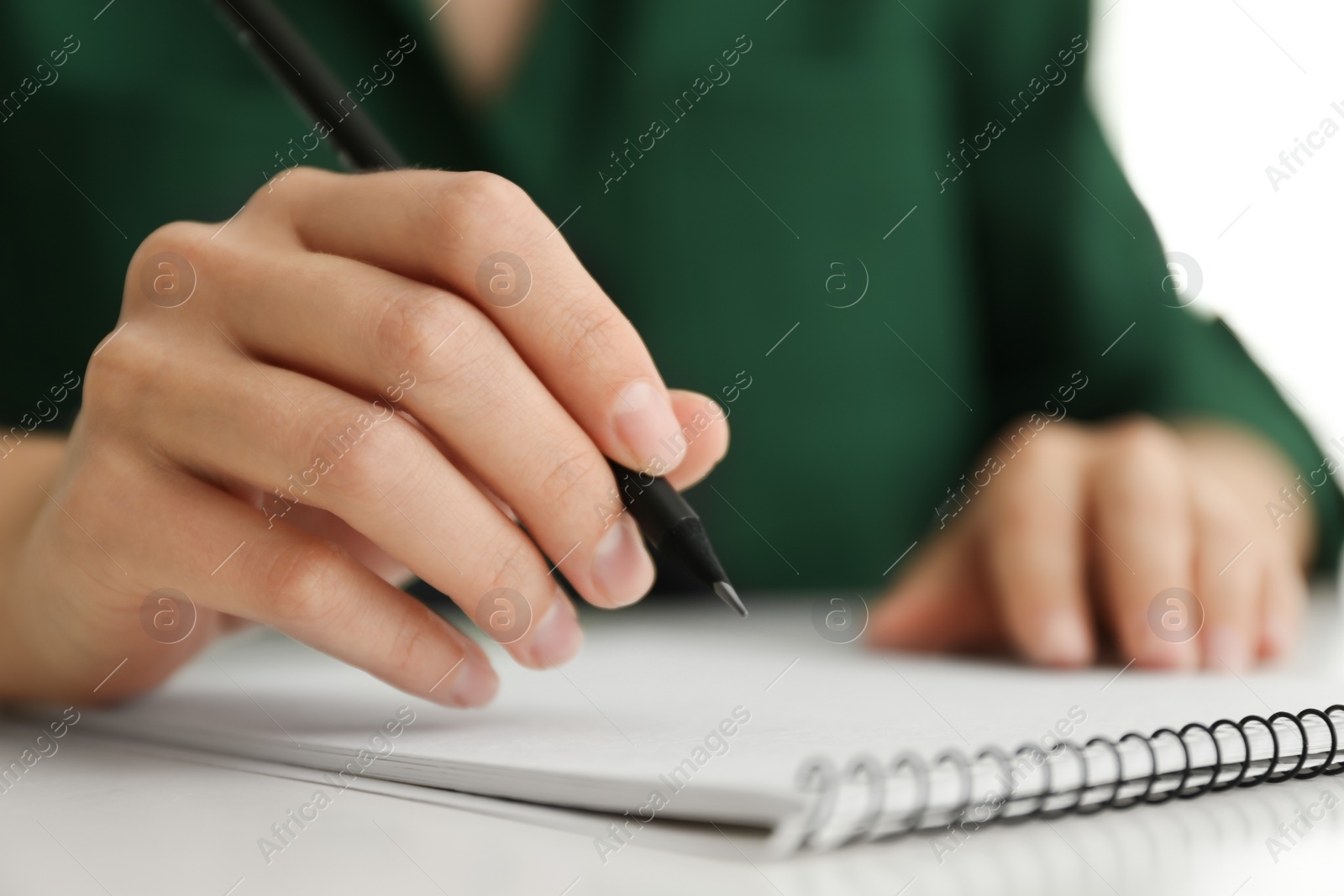Photo of Woman drawing with pencil in notepad at white table, closeup