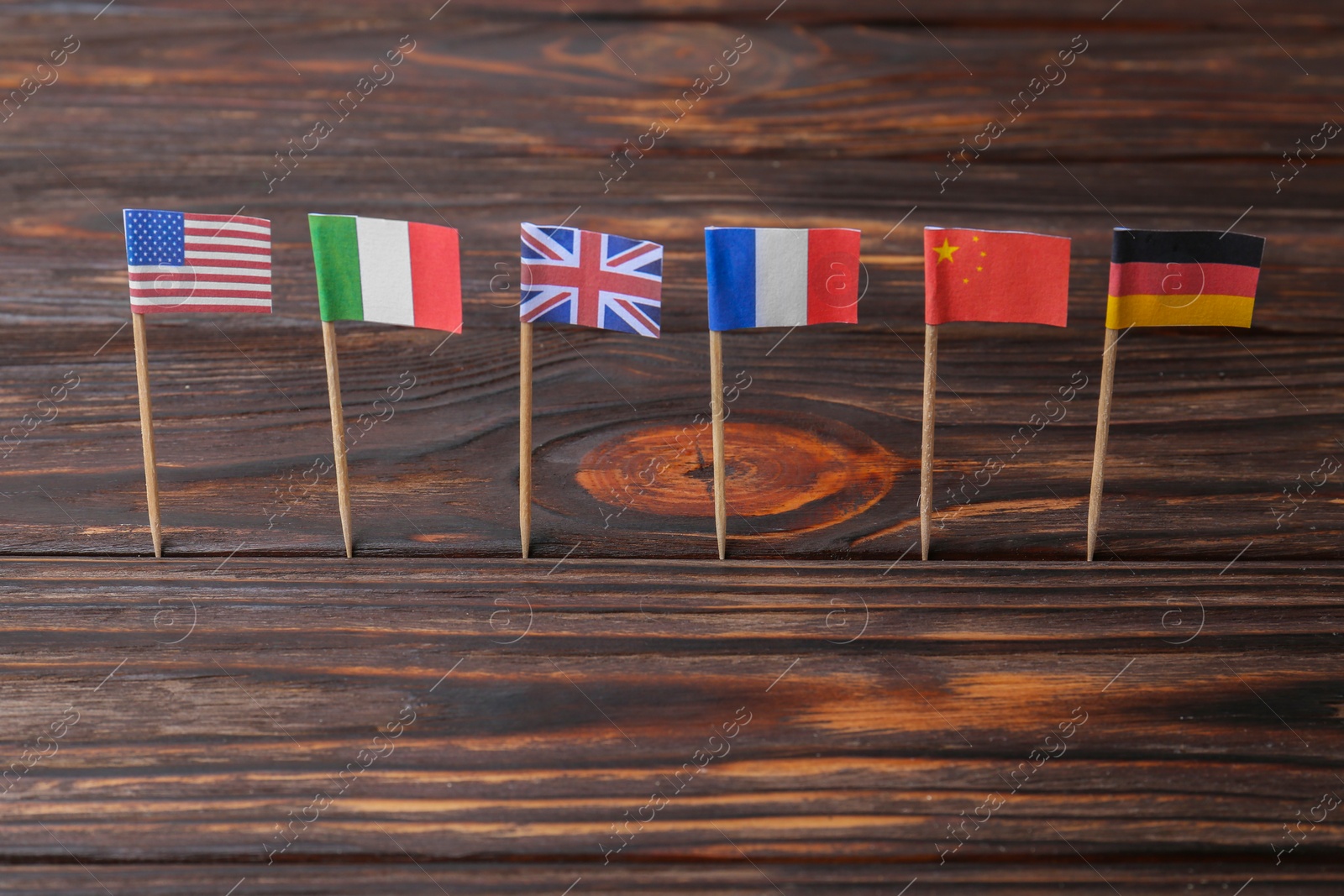 Photo of Many small paper flags of different countries on wooden table