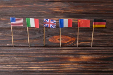 Photo of Many small paper flags of different countries on wooden table