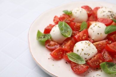 Tasty salad Caprese with tomatoes, mozzarella balls and basil on white tiled table, closeup. Space for text