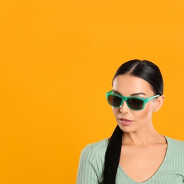 Photo of Beautiful woman wearing sunglasses on yellow background. Space for text