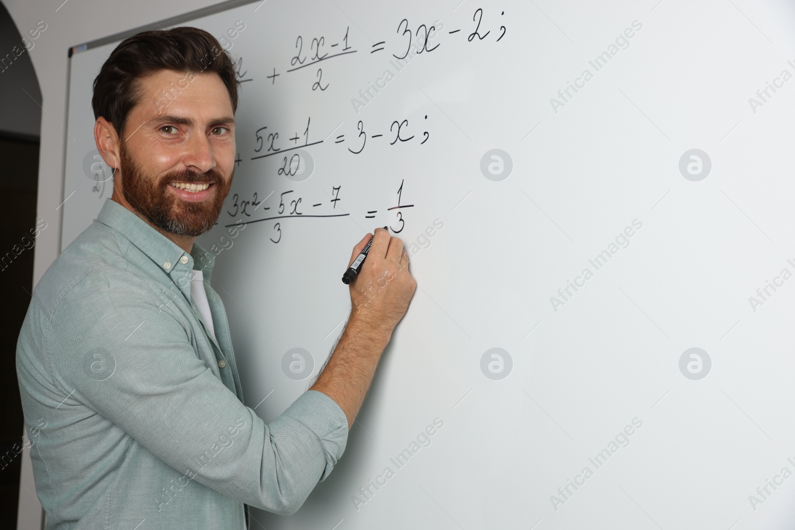 Photo of Happy teacher explaining mathematics at whiteboard in classroom