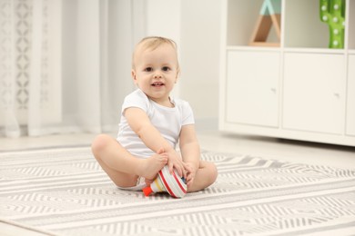 Children toys. Cute little boy playing with spinning top on rug at home