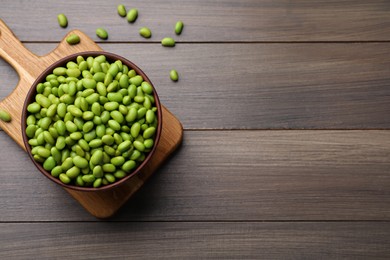 Photo of Bowl of delicious edamame beans on wooden table, flat lay. Space for text