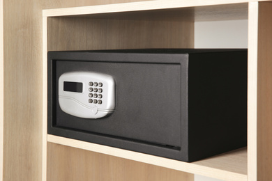Photo of Black steel safe with electronic lock in wooden closet