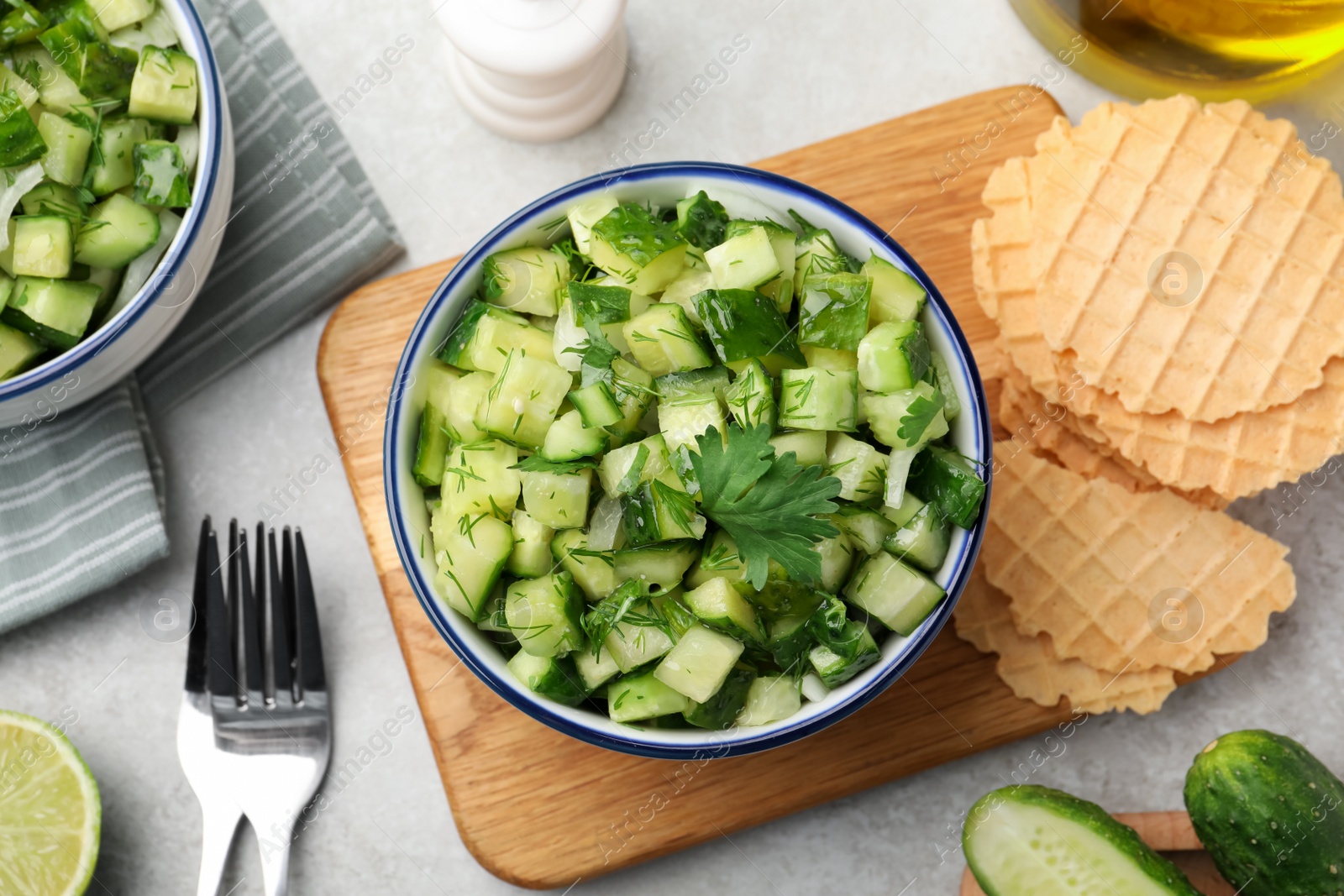 Photo of Bowl of delicious cucumber salad served on light table, flat lay