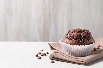 Photo of Tasty chocolate muffin on grey table, closeup. Space for text