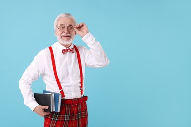 Photo of Portrait of stylish grandpa with glasses, bowtie and books on light blue background, space for text