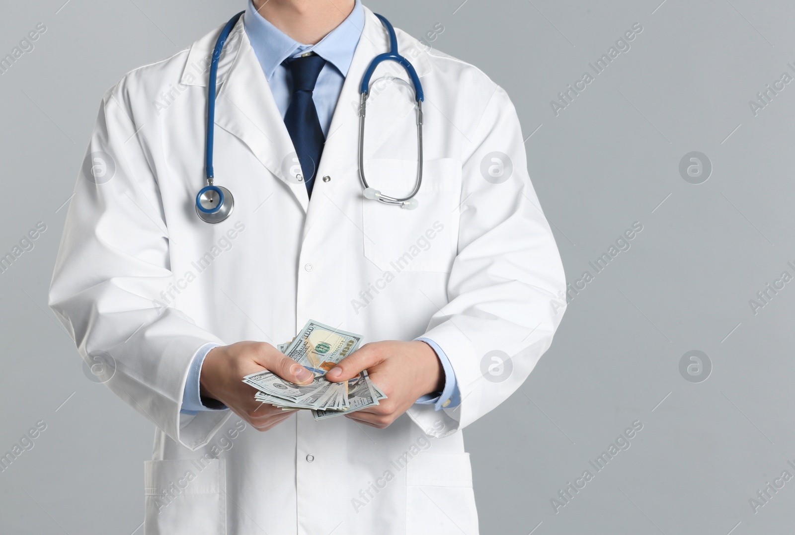 Photo of Doctor with bribe on grey background, closeup. Corruption in medicine