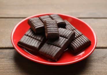 Photo of Red plate with delicious and healthy hematogen on wooden table, closeup