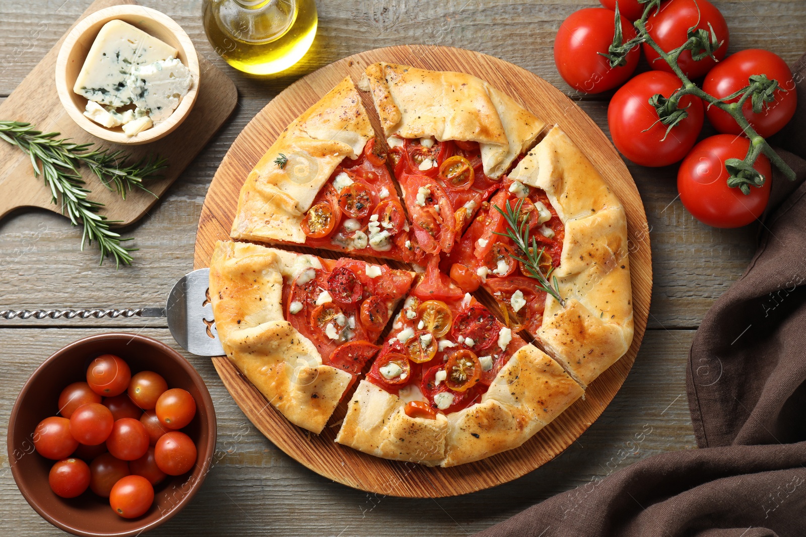 Photo of Flat lay composition of tasty galette with tomato, rosemary and cheese (Caprese galette) on wooden table