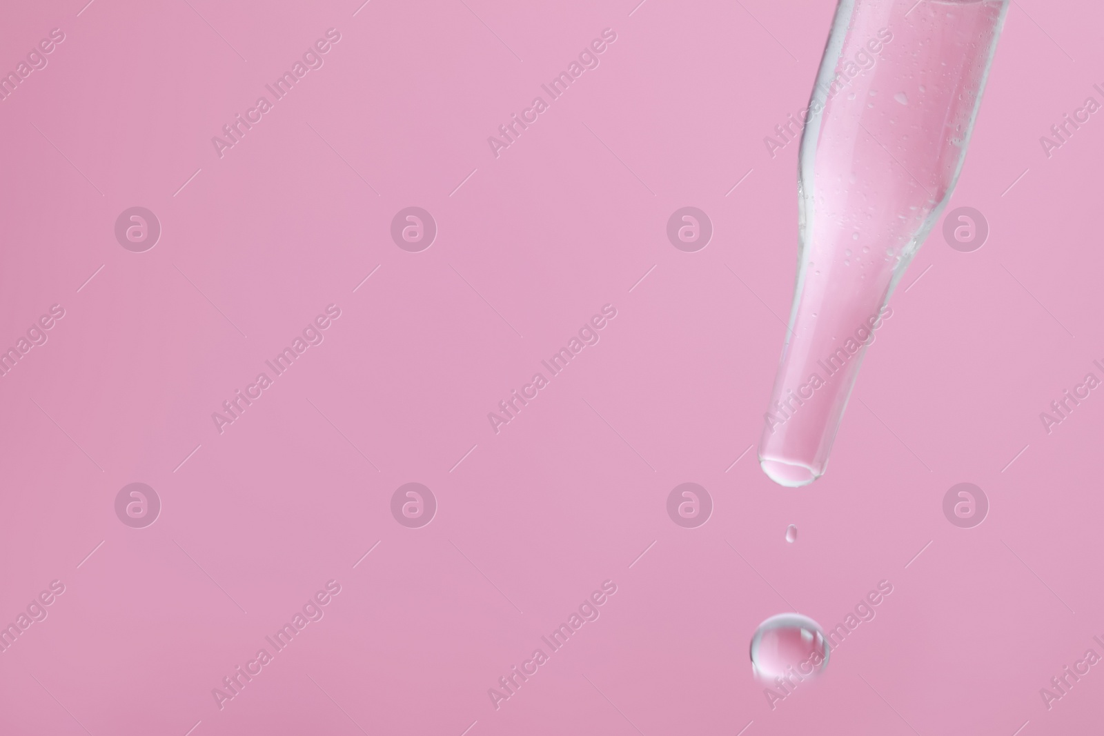 Photo of Dripping serum from pipette on pink background, closeup. Space for text