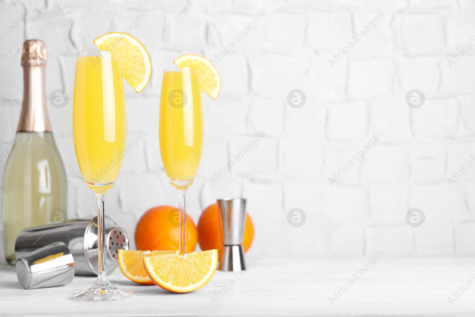 Photo of Fresh alcoholic Mimosa cocktails and fresh orange fruits on white wooden table, space for text